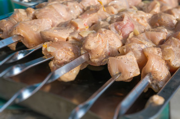 raw chicken breast meat coated with a marinade and onion, strung on skewers, a shish kebab preparation