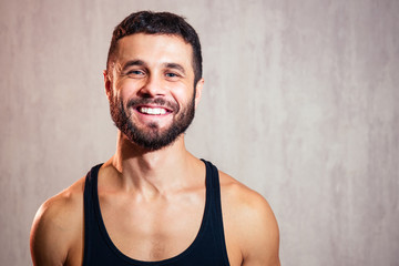 portrait of a handsome young man in a black T-shirt on a gray background. sports man smiling and flirting