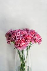 beautiful carnation flowers in a vase on a table . Bouquet of violet, purple and pink multicolor flower. Decoration of home. Wallpaper and background. Vertical photo