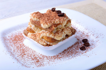 Piece of appetizing homemade tiramisu cake on plate in close up.
