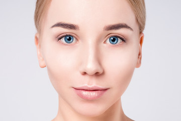Fototapeta premium Woman beautiful face portrait. Beauty Portrait. Beautiful Spa model Girl with Perfect Fresh Clean Skin. Blonde female looking at camera. Youth and Skin Care Concept.