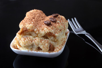 Piece of appetizing homemade tiramisu cake on plate in close up.