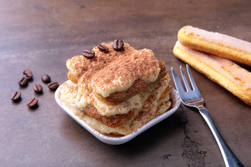 Piece of appetizing homemade tiramisu cake on plate in close up.