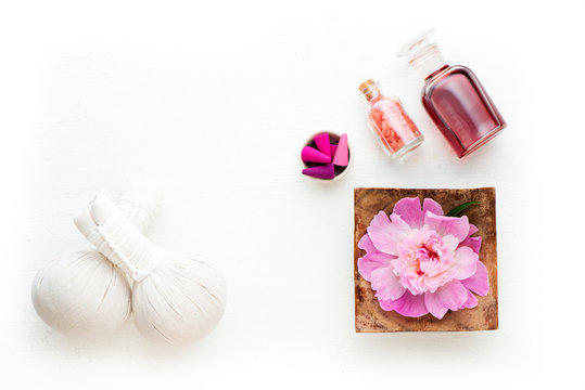 Spa, massage and aromatherapy concept. Thai herbal balls, massage aromatic oil, incense and flowers on a white background. Flat lay
