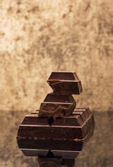 Blocks and pieces dark chocolate on a stone background background