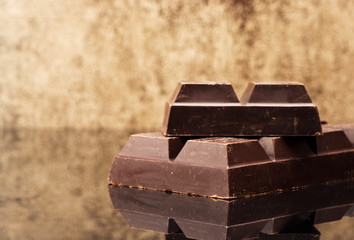 Blocks and pieces dark chocolate on a stone background and copy space for text