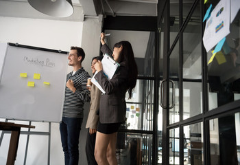 Group of young modern people in casual wear planning business strategy. Business team analyzing income charts and graphs. Setup studio shooting.