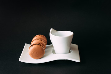 Set of cup of coffee and macarons against black background