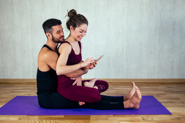 beautiful and young woman with curly hair and a sexy man doing selfie on yoga mat in floor. the concept of yoga in a pair and tantric yoga - obrazy, fototapety, plakaty
