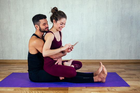 beautiful and young woman with curly hair and a sexy man doing selfie on yoga mat in floor. the concept of yoga in a pair and tantric yoga