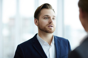 Young confident businessman communicating with his colleague