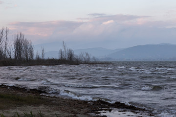 Moody lake shore at dusk, with waves and some warm sunset colors in the sky