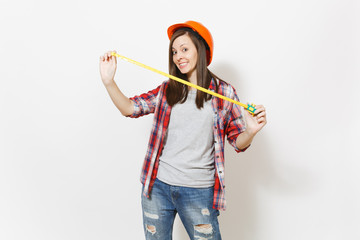 Young fun woman in casual clothes, protective construction orange helmet holding toy measure tape isolated on white background. Instruments, tools for renovation apartment room. Repair home concept.