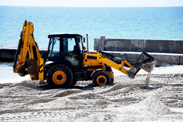 Tractor and sand. Repair work on the beach.