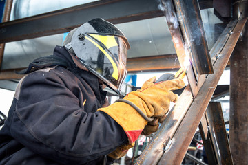 Worker in overalls mounts a metal structure.