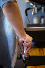 presses ground coffee using tamper