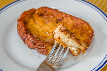 Torrija. It consists of a slice of bread that is soaked in milk or wine and, after being coated in egg, fried in a pan with oil. It is sweetened with sugar and is flavored with cinnamon.