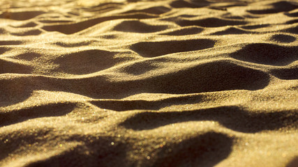 Clean sand with evening sun, shadows and soft focus. Wallpaper, background, bokeh.