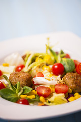 Colorful fresh vegetable salad with meatballs and corn seeds