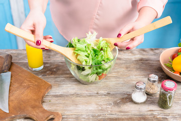 cropped shot of overweight woman cooking fresh salad for dinner in kitchen at home