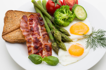 Fried eggs with bacon on the wooden table.