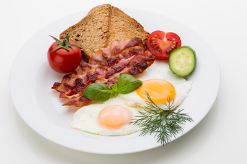 Fried eggs with bacon on the wooden table.