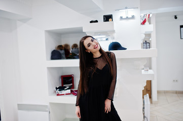 Brunette gorgeous girl in the clothing store boutique at black dress.