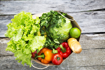 A full paper bag of healthy products stands on wooden table. Top view. From above.