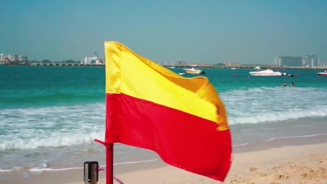 Red yellow flag. Beach Dubai Marina. Sunny day at the sea