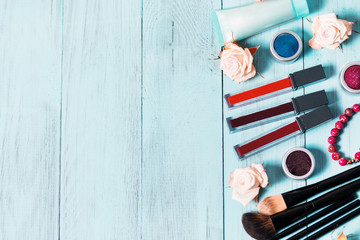 Cosmetics and makeup brushes on vintage blue wooden background, close up
