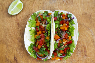 Corn tortillas with grilled pork on rustic wooden table, top view