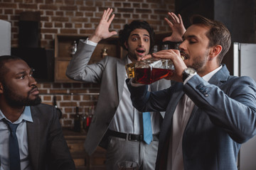 multiethnic businessmen looking at friend drinking alcohol beverages from bottles