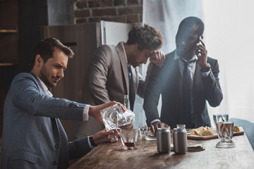 drunk multiethnic businessmen drinking whiskey together