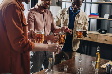cropped shot of smiling multiethnic men drinking alcoholic beverages together