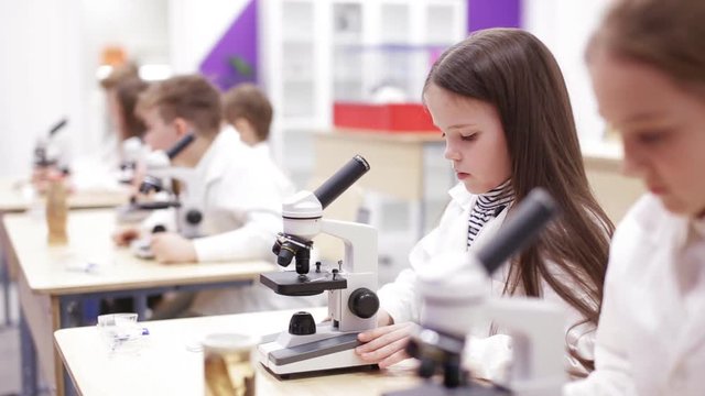 Schoolboys looking through microscope in laboratory