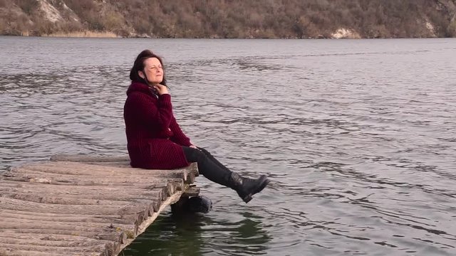 Beautiful woman sitting on a old bridge and looking at her