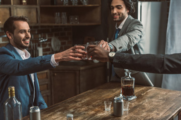 cropped shot of happy young businessmen clinking glasses of whisky and partying together