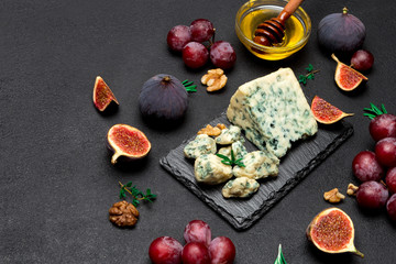 Slice of French Roquefort cheese and fruits on stone board