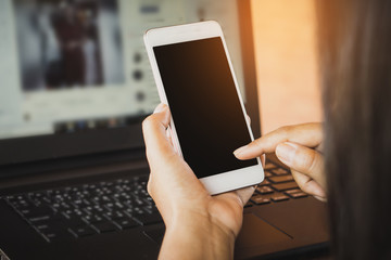Asian business woman using smart phone while working on laptop 