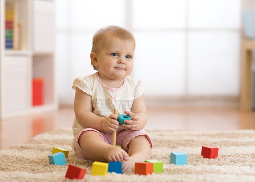 Cute baby toddler girl playing with wooden toys and having fun.