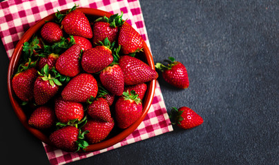 Strawberry. Fresh strawberry on black background with copy space for text. Heap of Red strewberry on a plate close up.
