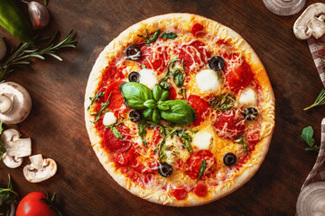 Hot pizza with Pepperoni  with vegetables and fresh ingredients on rustic wooden table. 