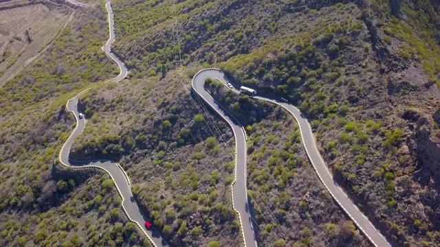 Aerial view of the long road in Tenerife Spain with the green trees on the mountain on the side of the road