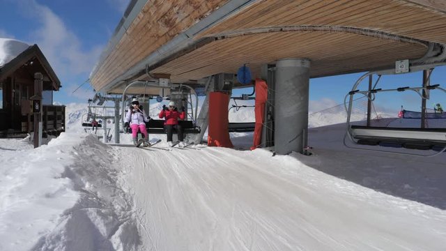 Skiers Climb In Chair Lift Oo The Top Mountain And Move Out Of It On The Slope