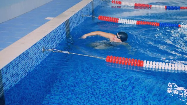 Female swimmer reaches the end of a lane, then pushes back. 4K.