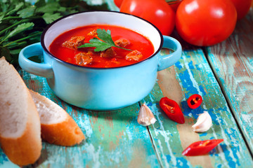 Tomato soup in a blue bowl. Rustic style. Wooden background.