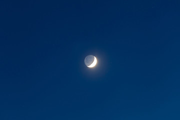 Moon - Waxing Crescent and grey light against blue starry sky background