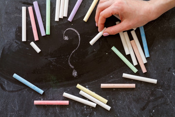 hand with a piece of chalk drawing a question mark