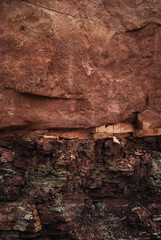 Background of natural sandstone, banded, red or brown, colored texture background. Stone surface texture closeup. Deposit, quarry for the extraction of sandstone stone. Mining, natural resources