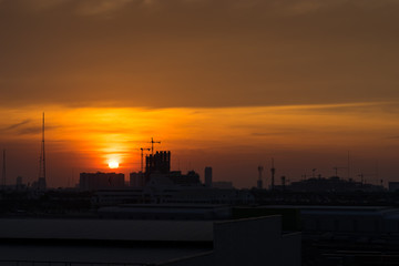 Naklejka premium sunset orange sky cityscape and construction site silhouette